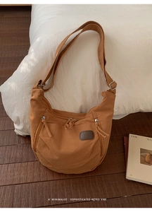 Detail view of brown canvas messenger bag with multiple zipper pockets and adjustable strap