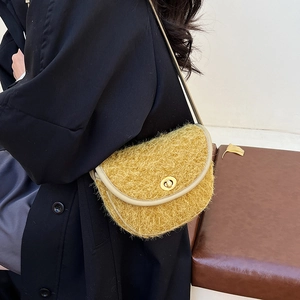 Dettaglio borsa a sella gialla in peluche con fibbia dorata su un cappotto nero