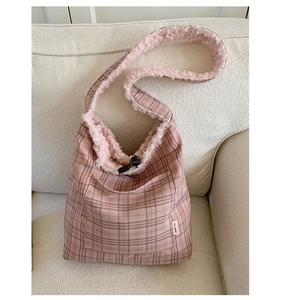 Detail of pink plaid tote bag featuring fluffy fleece trim and minimalist logo tag
