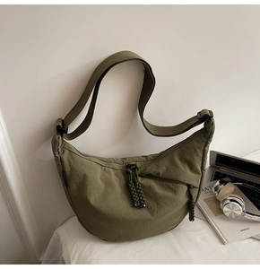 Detail of army green nylon crescent bag with adjustable strap and textured fabric surface