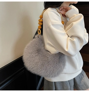 Detail of grey faux fur shoulder bag with decorative wooden bead strap for autumn winter