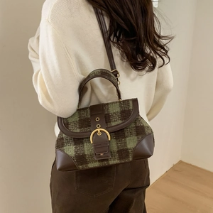 Detail view of vintage green plaid handbag with premium brown leather trim on a model