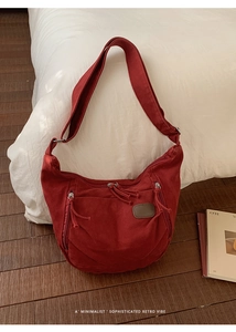 Detail of dark red canvas dumpling bag showing multiple zippers and retro leather patch