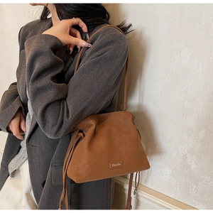 Detail of caramel leather bucket bag with drawstring closure and wooden bead accents