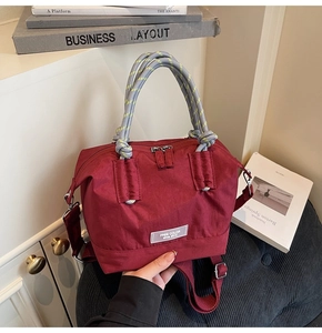 Détail du sac bandoulière bordeaux avec poignée en corde tissée et étiquette argent