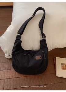 Détail du sac croissant en toile noire avec poches multiples et empiècement cuir