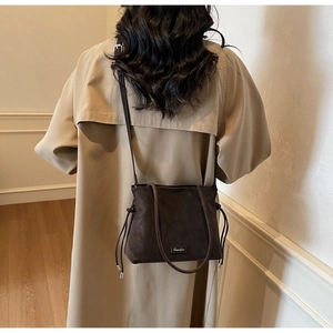 Detail of dark brown matte leather bag with drawstring and brand logo plaque