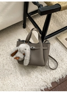 Detail of grey pebble leather handbag with silver lock and a cute rabbit charm