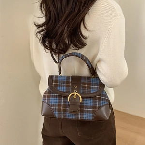 Detail of vintage plaid wool handbag with brown leather trim and golden round buckle