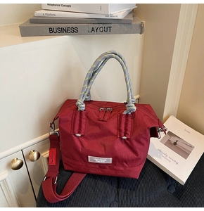 Détail d'un sac à main en nylon bordeaux avec poignées tressées et bandoulière amovible