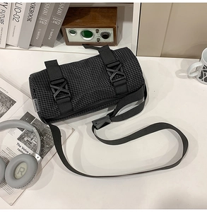 Detail der karierten Zylindertasche mit Nylonriemen auf einem minimalistischen Tisch