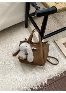 Brown lychee leather bucket bag with a cute rabbit pendant on a vintage chair