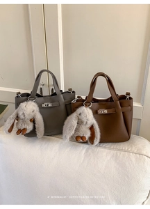 Detail of grey and brown lychee grain leather handbags with metal turn-lock and fur bunny