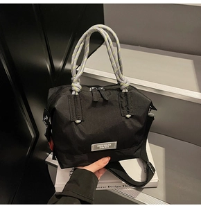 Détail du sac en nylon noir avec poignées en corde jaune néon et plaque de logo en métal