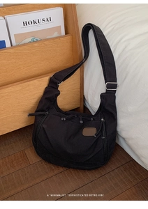Detail of black nylon crossbody bag with side metal zipper and wide adjustable strap