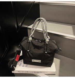 Détail du sac cabas en nylon noir avec poignées tissées bicolores et logo de la marque