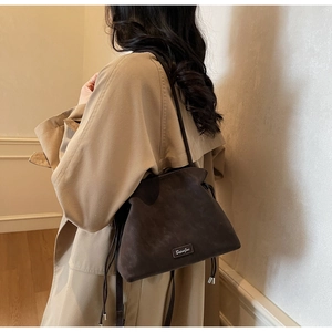 Detail of dark brown matte bucket bag showing drawstring closure and silver brand logo