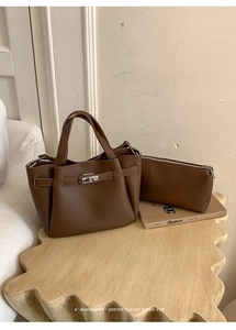 Brown lychee leather bucket bag with silver clasp and matching zipper pouch on wood table