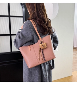 Detailed shot of pink faux leather tote bag with cute brown bear charm on grey coat