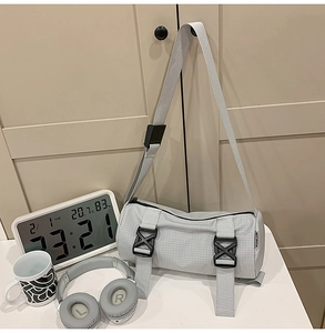 Detailaufnahme der hellgrauen Zylindertasche mit Gitterstruktur und Schnallenriemen
