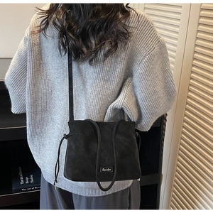 Detail of black matte leather bucket bag with drawstring and thin shoulder strap