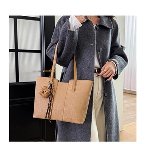 Close-up of khaki tote bag featuring premium lychee grain leather and cute bear pendant