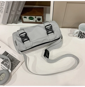 Detail der hellgrauen Gitter-Zylindertasche mit schwarzer Schnalle auf Schreibtisch