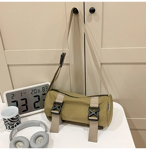 Detailansicht der olivgrünen Zylindertasche mit Schnallenriemen an einem Schrank