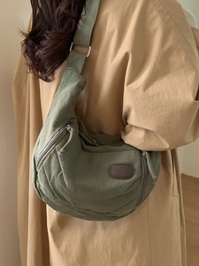 Sac hobo en toile vert foncé avec bandoulière réglable porté par un mannequin en extérieur