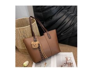 Detailed view of brown lychee grain leather tote bag with cute teddy bear charm
