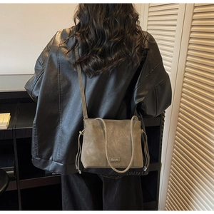 Detailed view of olive green suede crossbody bag with metallic logo and knot accents