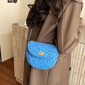Borsa a sella blu in tessuto peloso con chiusura dorata indossata da una modella