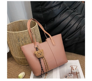 Detail of dusty pink faux leather tote bag with a cute plush bear charm and woven cord