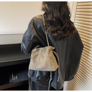 Detail of taupe frosted drawstring bucket bag with slim strap on model back view