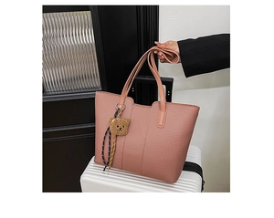 Detail of dusty pink tote bag with pebble leather texture and cute brown plush bear charm