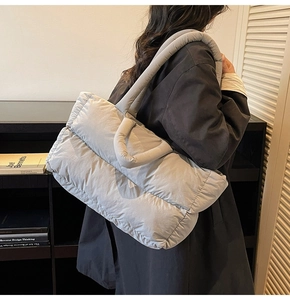 Model wearing a light grey quilted puffer tote bag with soft padded straps for autumn