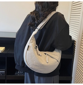 Detail of the oversized crescent bag featuring a woven rope zipper and textured fabric