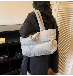 Detail of grey puffer tote bag showing soft quilted texture and wide shoulder strap