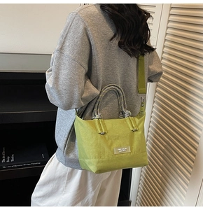 Sac fourre-tout vert en nylon avec bandoulière, porté par un mannequin en intérieur