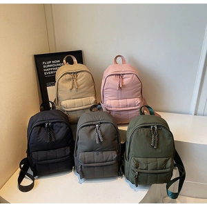 Close-up of lightweight quilted backpacks in five colors with woven zipper pulls and soft texture