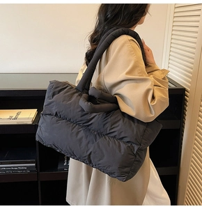 Quilted black tote bag with padded handles shown in a minimalist urban lifestyle setting