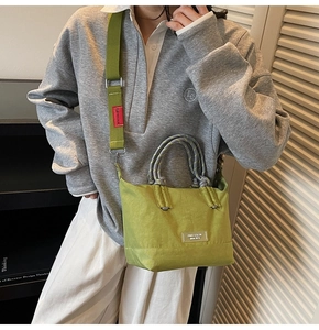 Détail du sac seau en toile vert avocat avec poignées tressées grises et étiquette de marque