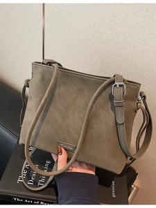 Minimalist matte grey-green bucket bag with adjustable strap and metal brand logo
