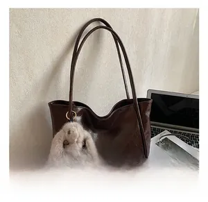 Detail of dark brown glossy tote bag with plush rabbit charm and double shoulder straps