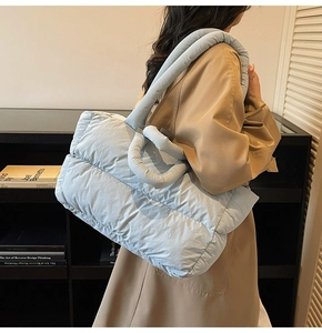 Detail of light blue puffer tote bag featuring quilted fabric and tubular padded handles