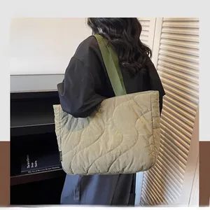 Detail view of green quilted down tote bag with wide shoulder strap and brand label