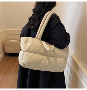 Detailed macro view of cream quilted puffer tote bag with soft padded nylon texture