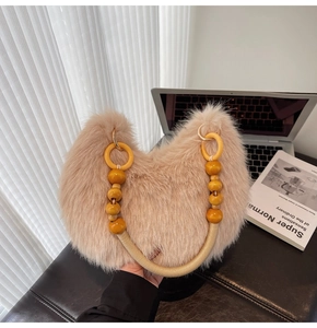 Détail d'un sac peluche beige avec poignée perlée sur un bureau en cuir moderne et chic