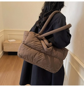 Detailed side view of coffee brown puffer tote bag featuring quilted padded structure