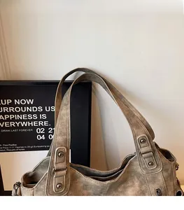 Close-up of retro grey-brown leather tote bag with rivet details and wide shoulder strap